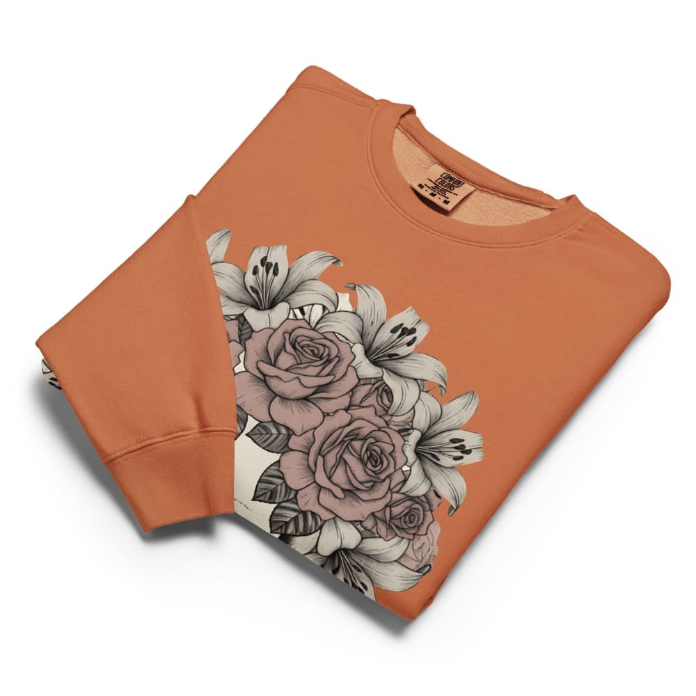 Folded orange sweatshirt with floral design on a white background