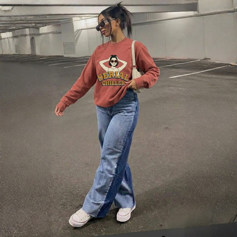 Person wearing a red sweatshirt with graphic design and blue jeans in an indoor setting