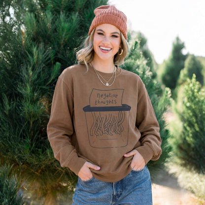 Woman wearing a brown sweatshirt with a graphic design outdoors