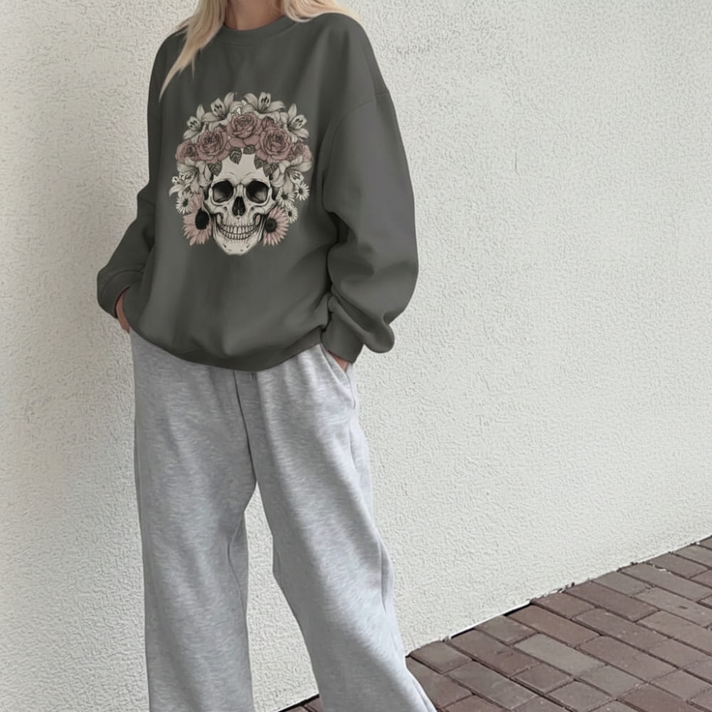 Person wearing a dark gray sweatshirt with a skull and floral design against a light wall.