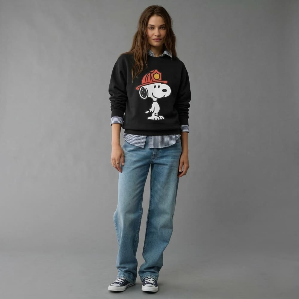 Person wearing a black sweatshirt with a dog graphic and blue jeans on a gray background