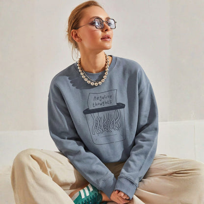 Person wearing a blue sweatshirt with a graphic design sitting on a white couch.