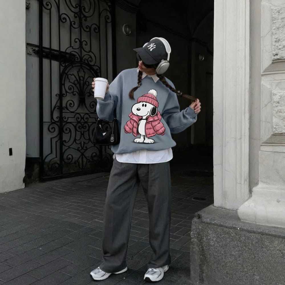 Person wearing a blue sweatshirt with a cartoon character design, standing in front of a building entrance.