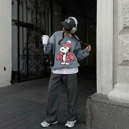 Person wearing a blue sweatshirt with a cartoon character design, standing in front of a building entrance.