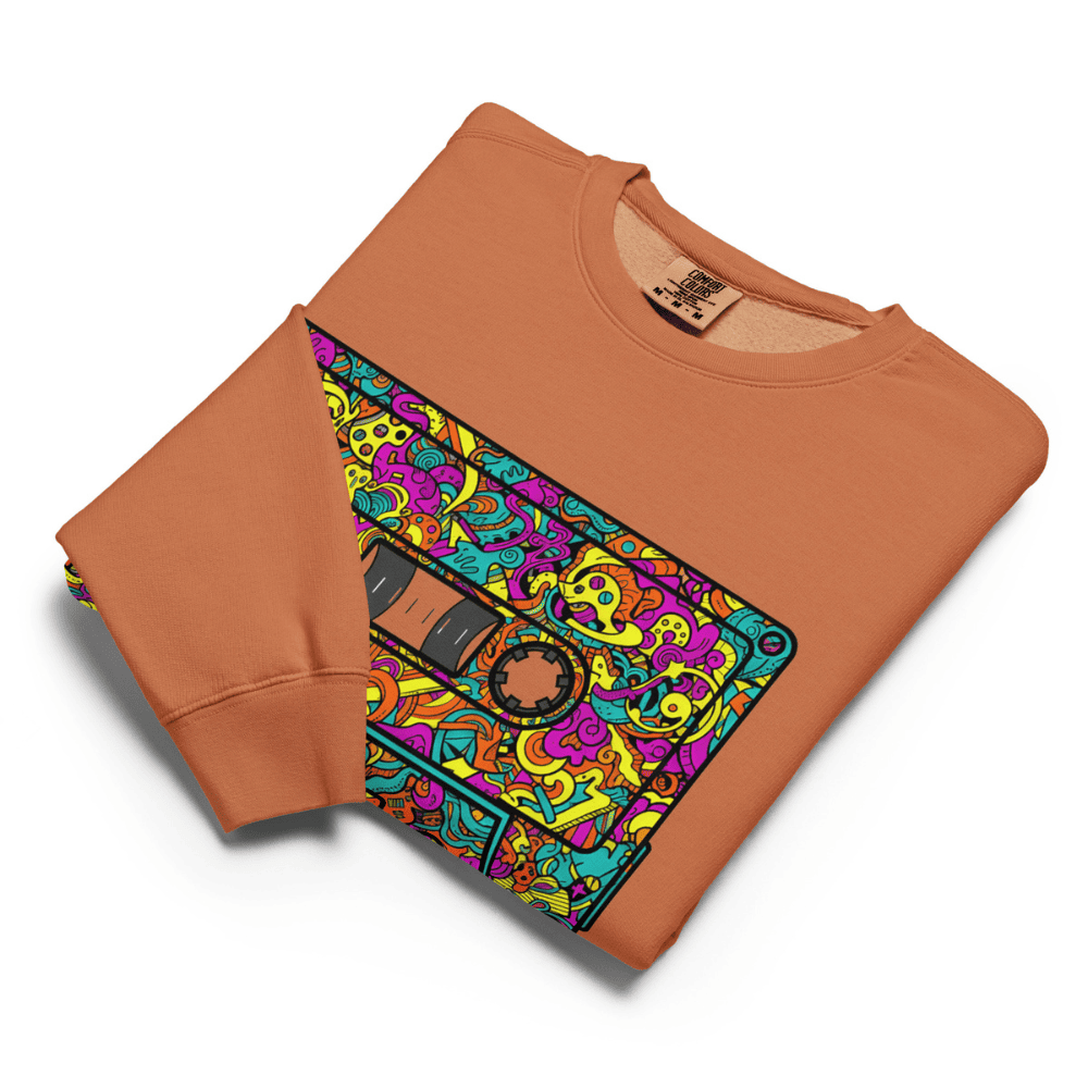 Folded orange sweatshirt with colorful cassette tape design on a white background