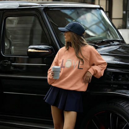 Woman in pink sweatshirt with 'LOVE' print and navy skirt standing next to a black SUV.