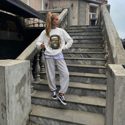 Person wearing a white sweatshirt with a kettlebell design on stone steps.