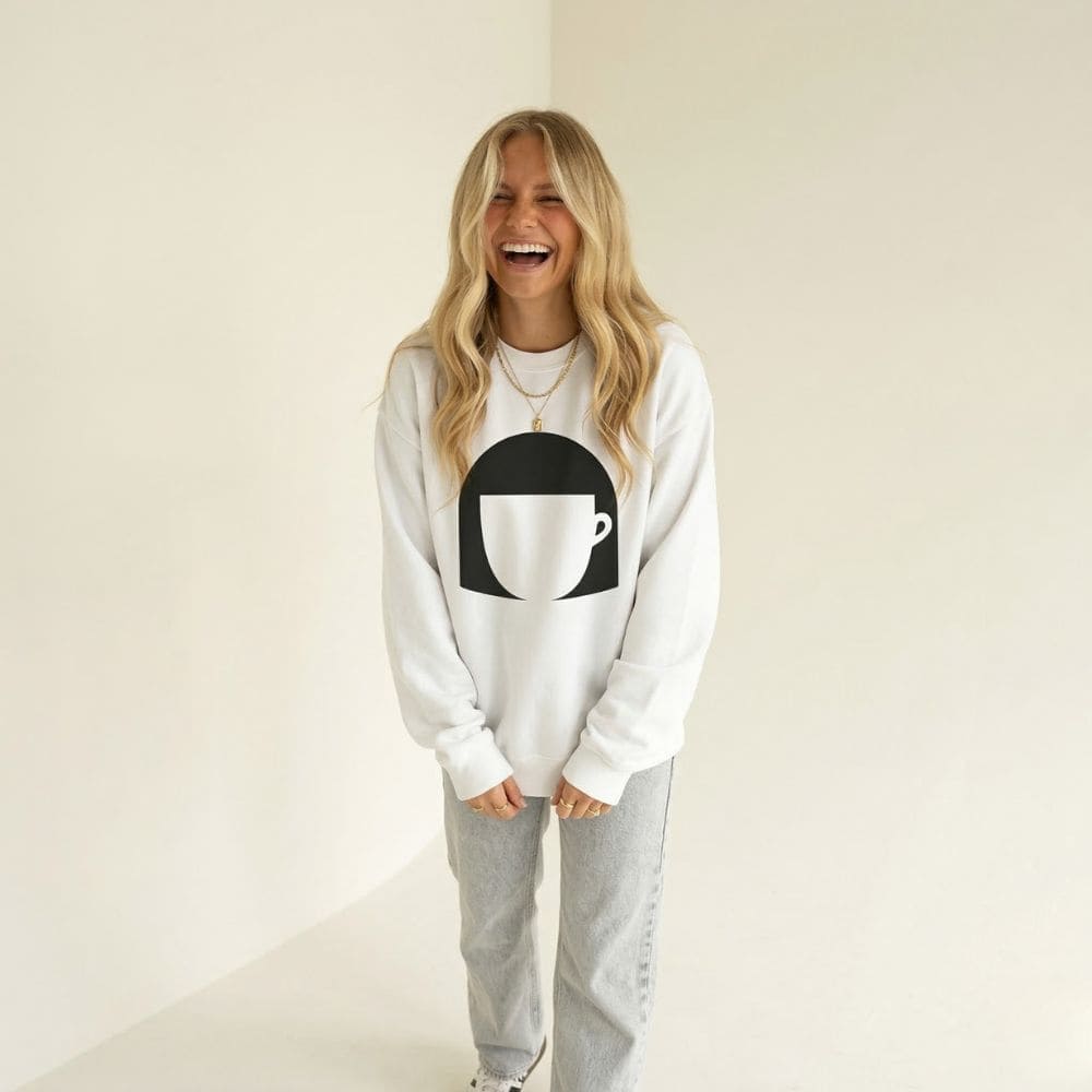 Person wearing a white sweatshirt with a black and white graphic design on a plain background