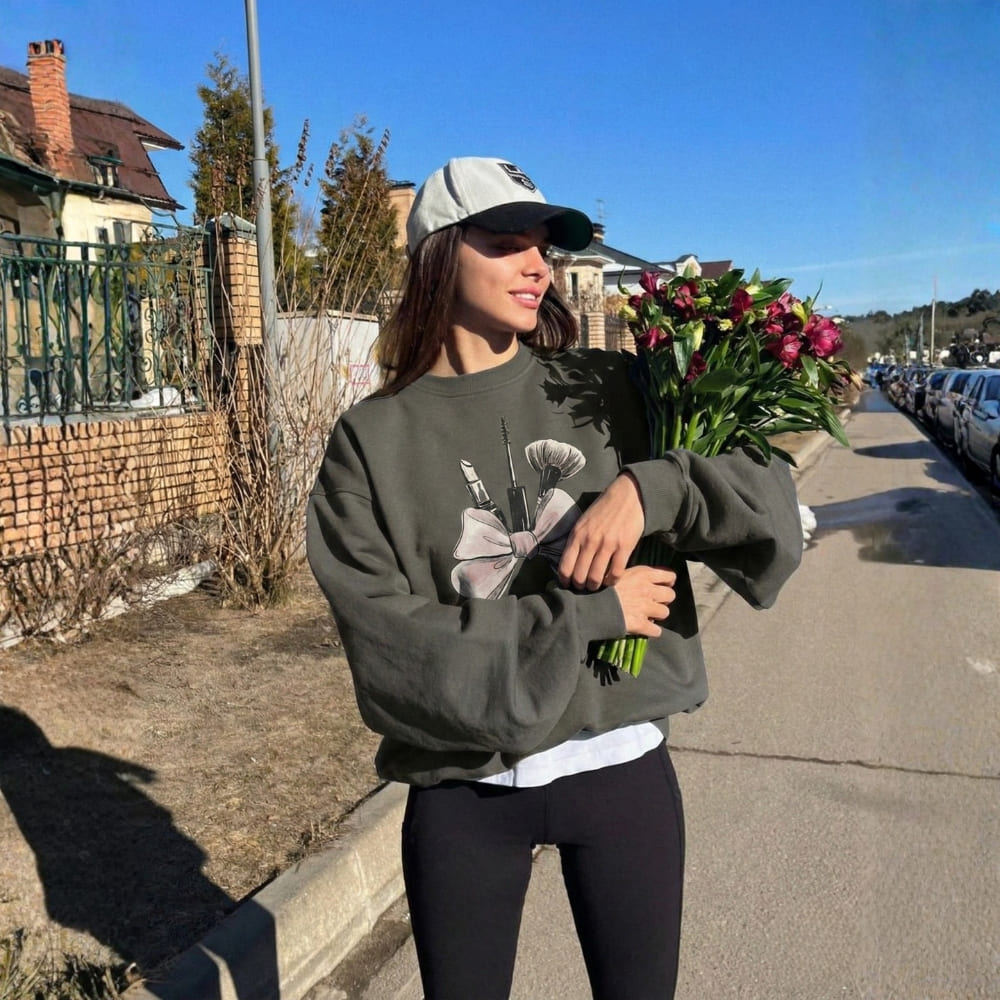 Woman holding flowers on a sidewalk with houses and cars in the background