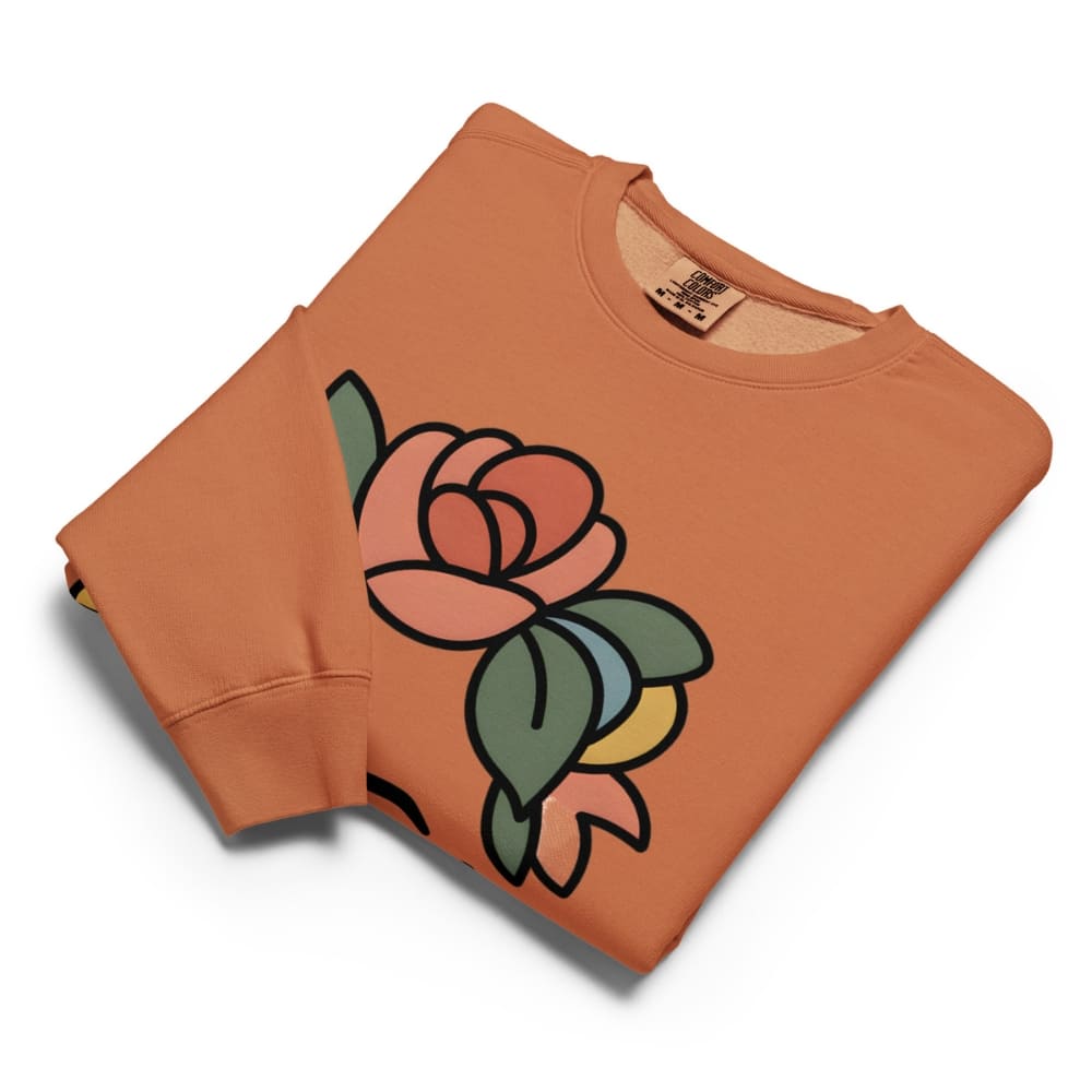 Folded orange sweatshirt with a colorful rose graphic on a white background