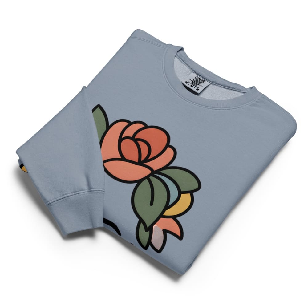 Folded light blue sweatshirt with a colorful rose design on a white background