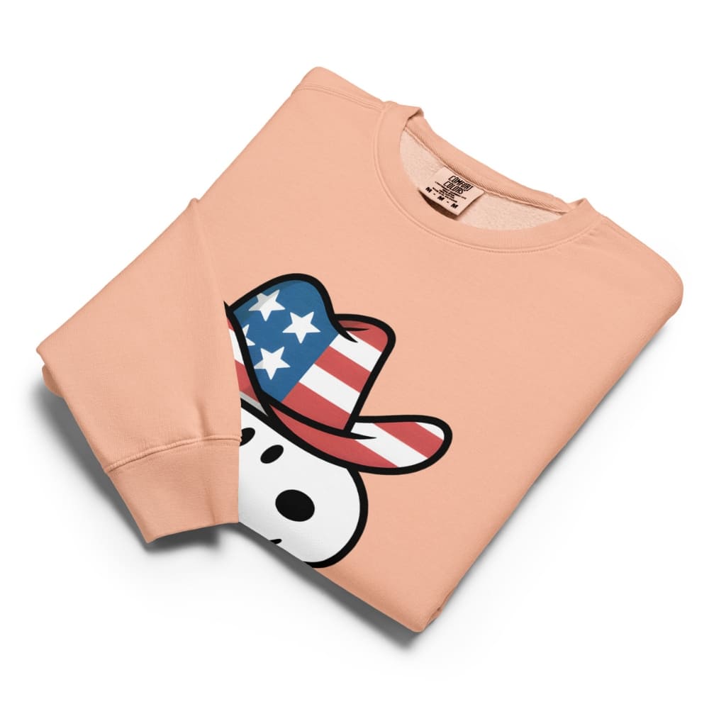 Folded peach-colored sweatshirt with a cartoon character wearing an American flag hat on a white background