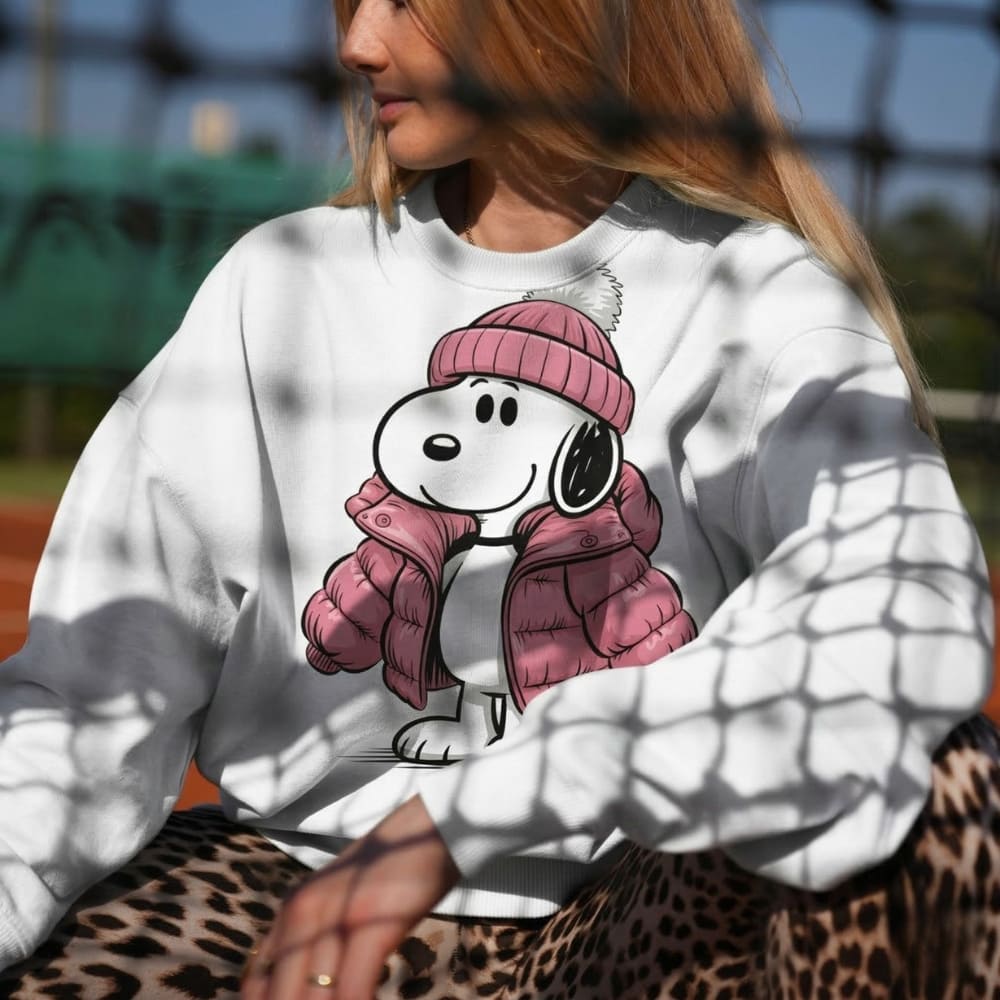 Person wearing a white sweatshirt with a cartoon character design, sitting outdoors.