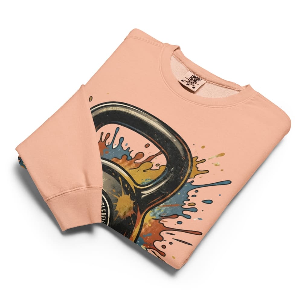 Folded peach-colored sweatshirt with a colorful graphic design on a white background