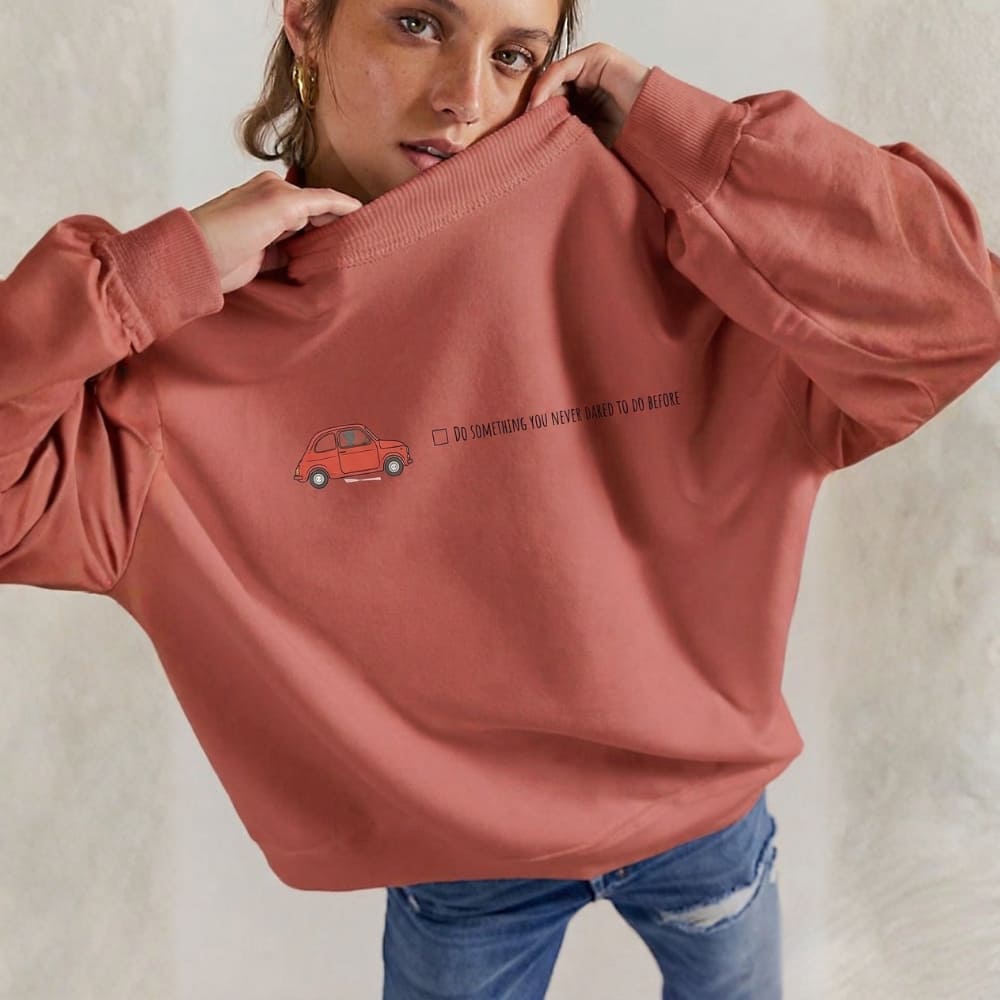 Person wearing a red sweatshirt with a small car graphic and text on a plain background