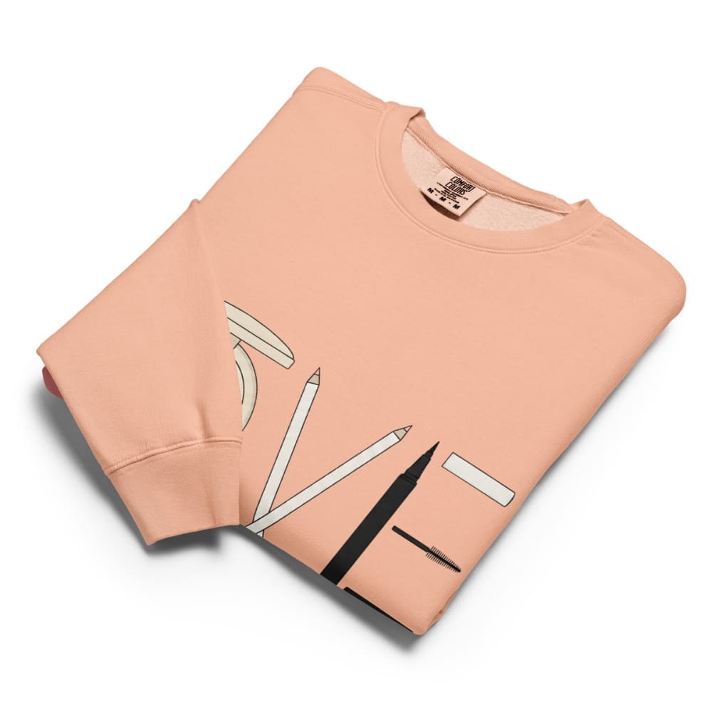 Folded peach-colored sweatshirt with a graphic design on a white background