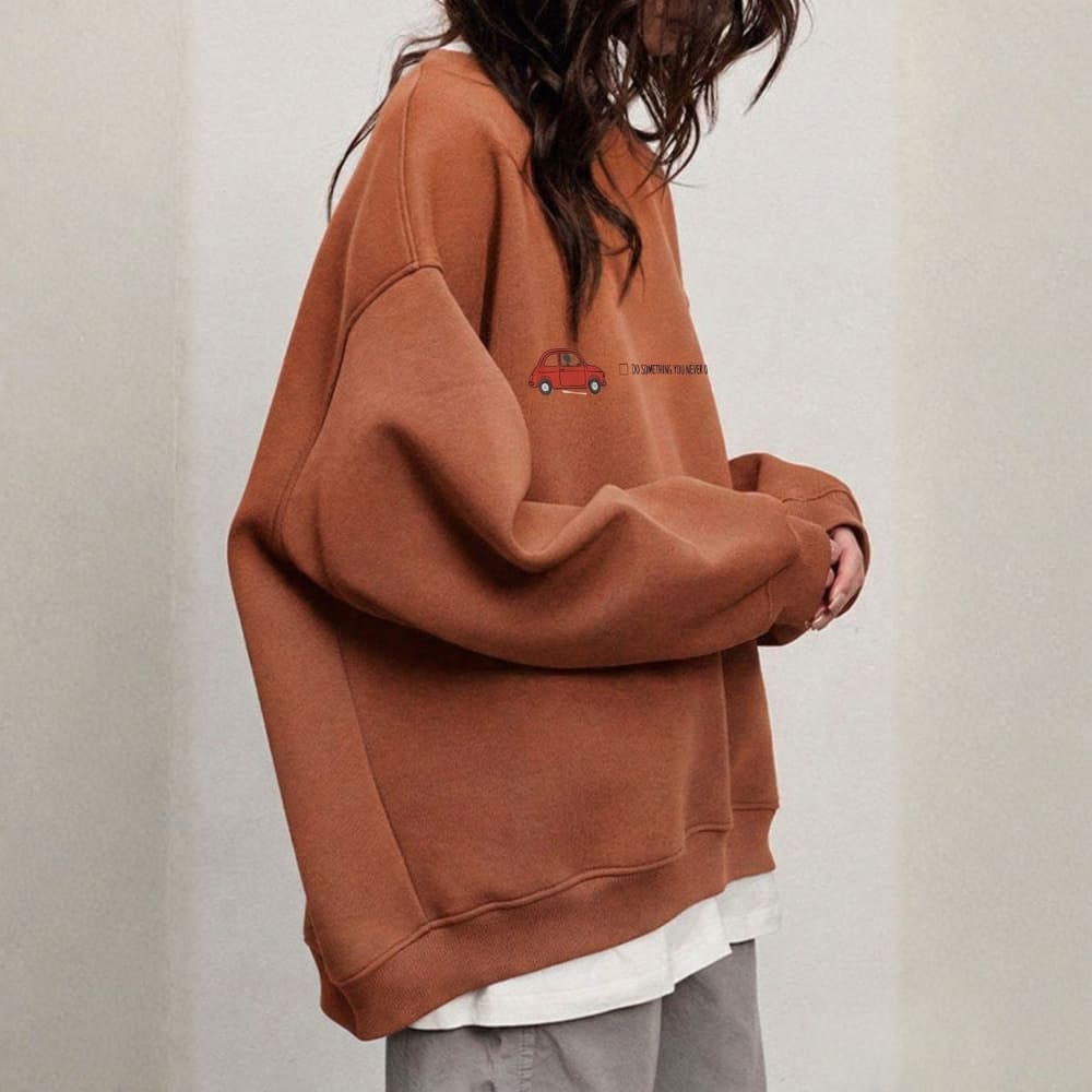 Person wearing a orange sweatshirt with a small red graphic on a plain background