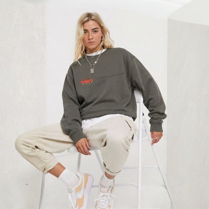 Person wearing a gray sweatshirt with a red graphic, beige pants, and white sneakers on a white background
