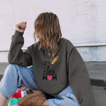 Person wearing a sweatshirt with a unique design on the back, sitting against a white wall.