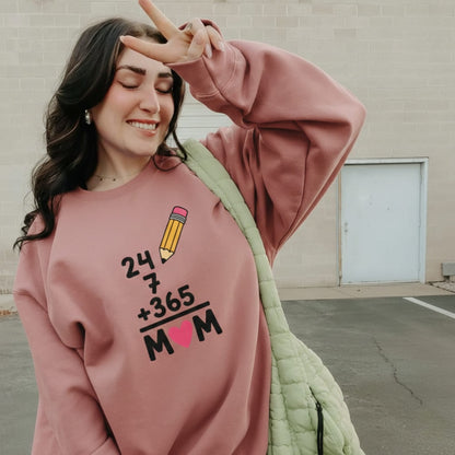 Woman wearing a pink sweatshirt with a unique design, standing against a plain wall.