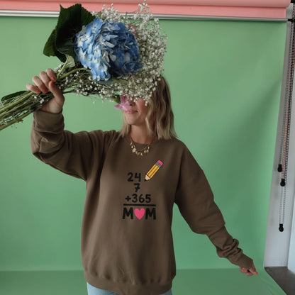 Person wearing a brown sweatshirt with text and graphics, holding flowers against a green background