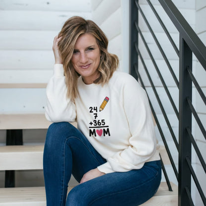 Woman wearing a white sweatshirt with text and a heart symbol, sitting on stairs.