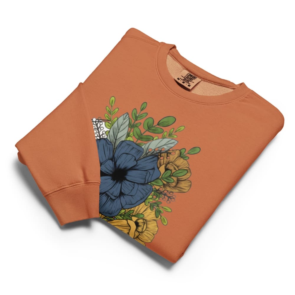 Folded orange sweatshirt with floral design on a white background