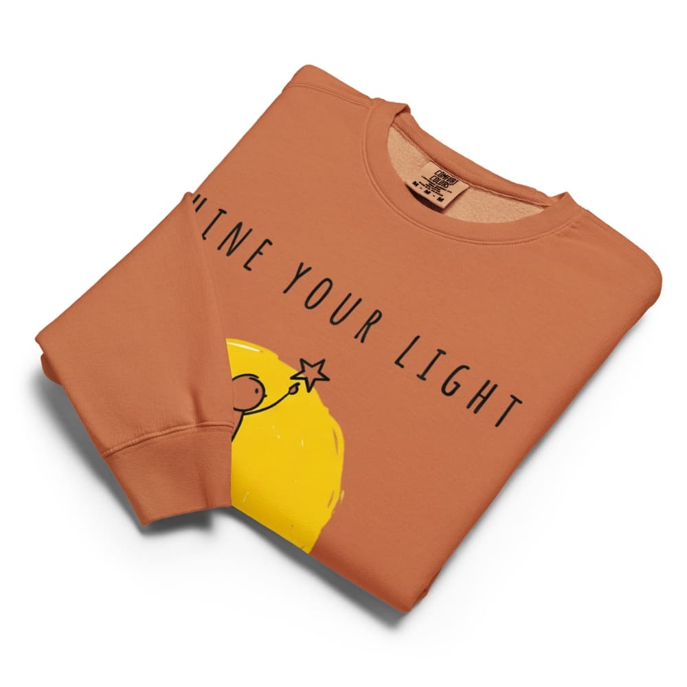 Folded orange sweatshirt with yellow graphic and text on a white background
