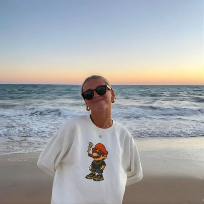 Person wearing a white sweatshirt with a graphic design on a beach at sunset