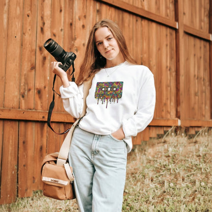 Person holding a camera with a colorful bag design, standing against a wooden fence.