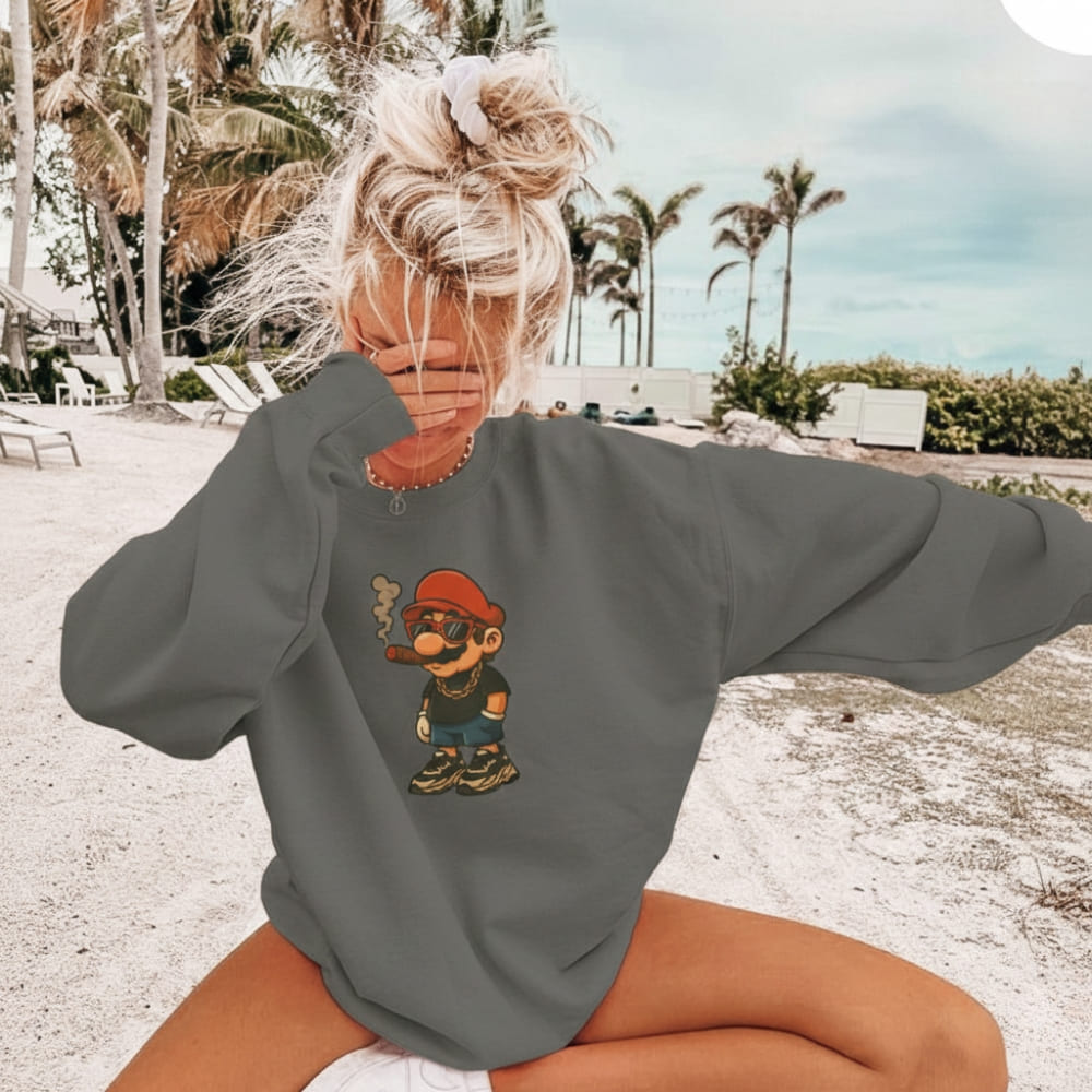 Person wearing a gray sweatshirt with a cartoon character on a beach