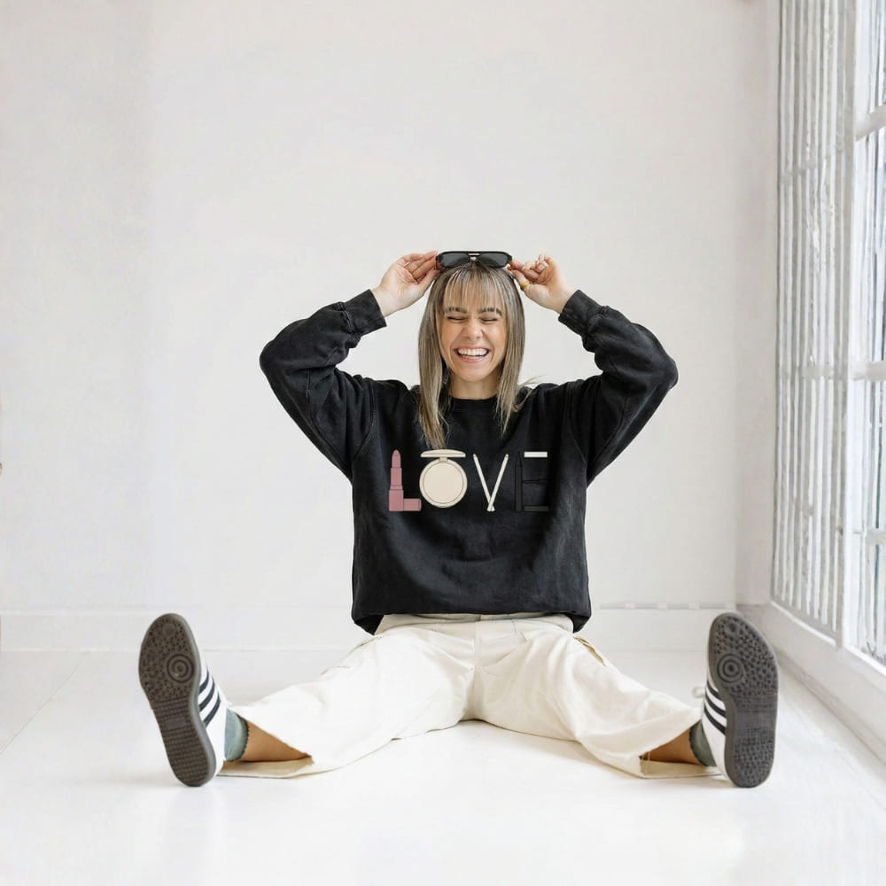 Person wearing a black sweatshirt with 'LOVE' printed on it, sitting on the floor in a bright room.
