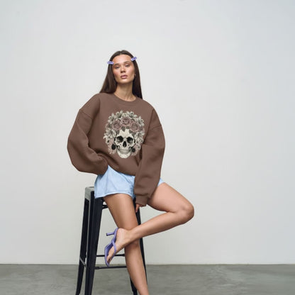 Woman wearing a brown sweatshirt with a skull design, sitting on a black stool against a plain background.