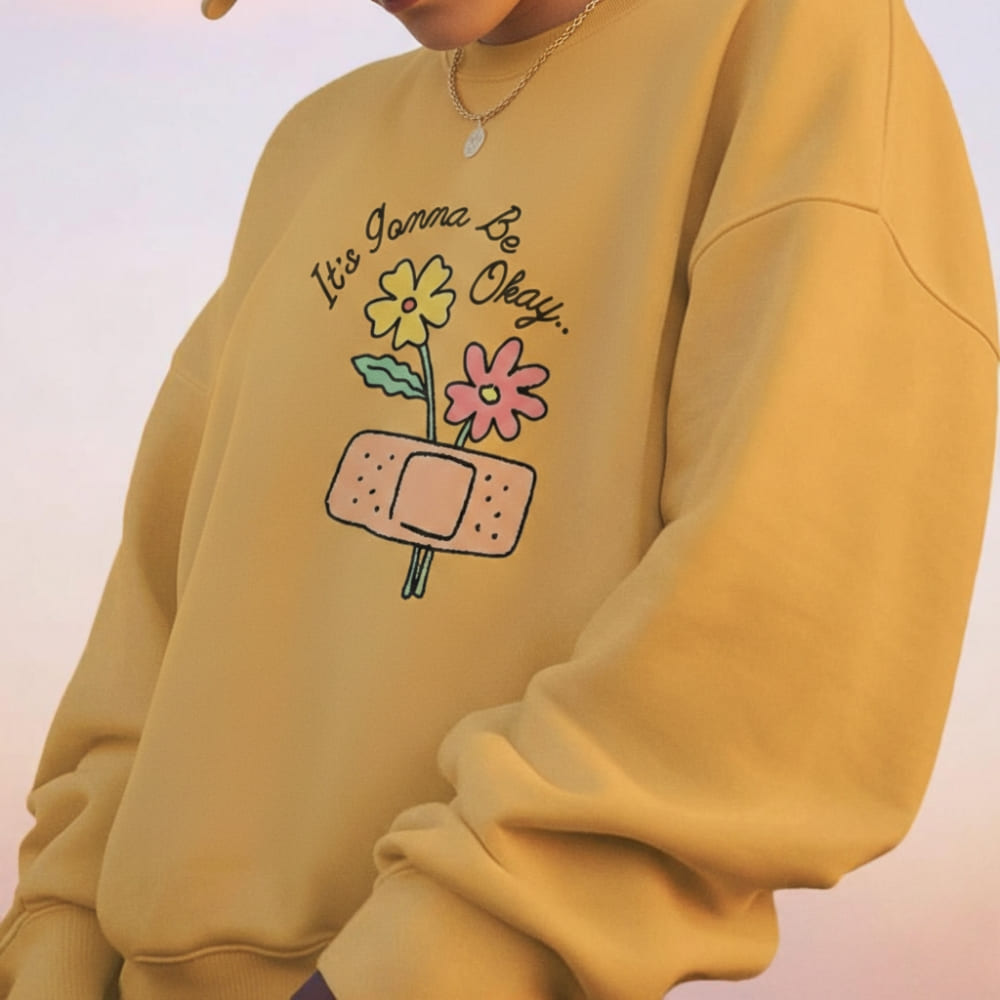 Yellow sweatshirt with floral design and text on a light pink background