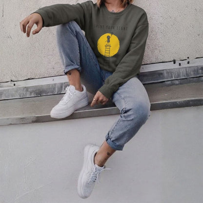 Person wearing a gray sweatshirt with a yellow graphic, sitting on a concrete ledge.