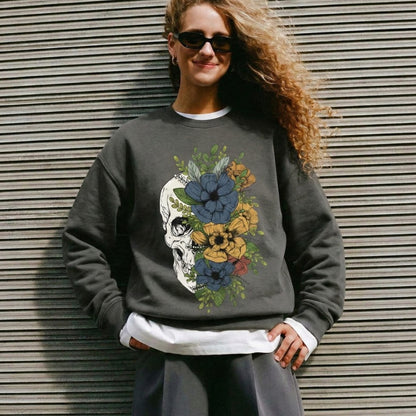 Person wearing a dark gray sweatshirt with a floral skull design against a metallic wall.