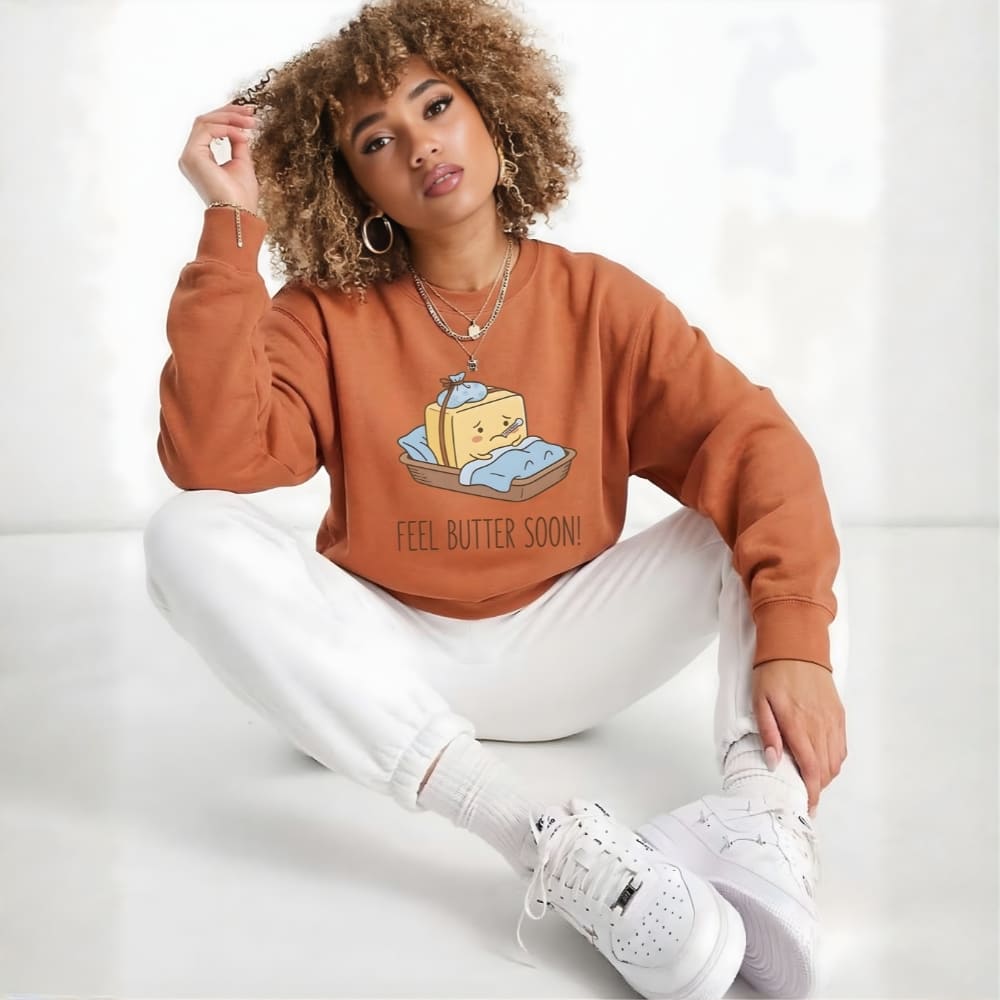 Person wearing a orange sweatshirt with a cheese graphic and text, sitting on a white background