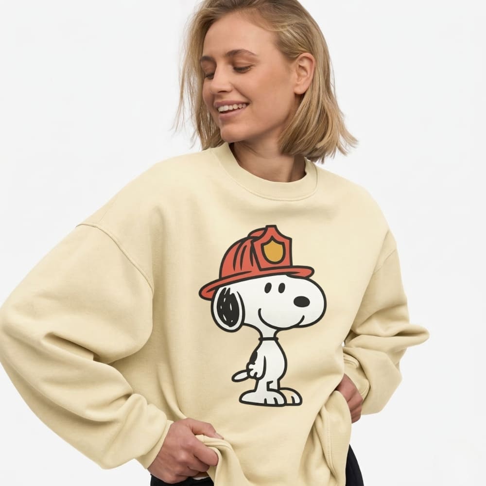 Person wearing a beige sweatshirt with a cartoon character design on a plain background