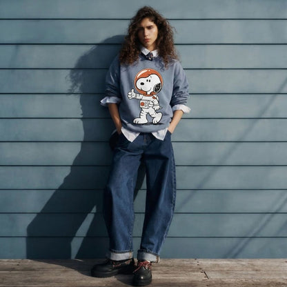 Person wearing a blue sweater with an astronaut graphic against a wooden wall