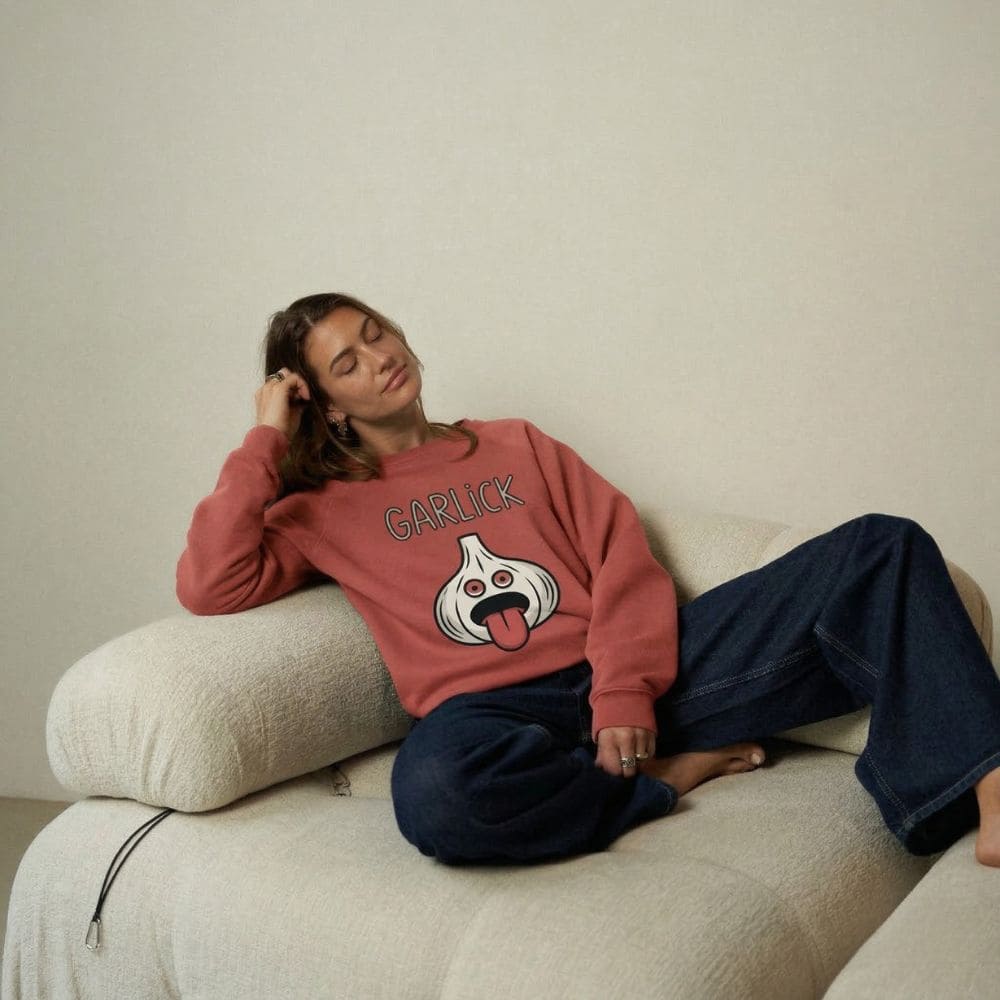 Person wearing a red sweatshirt with a graphic design sitting on a beige couch.