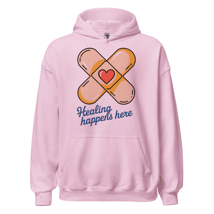 Pink hoodie with bandage design and 'Healing happens here' text on a white background