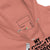 Close-up of a pink hoodie with text and branding details.