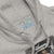 Gray hoodie with a logo on the chest and a graphic design on the sleeve.