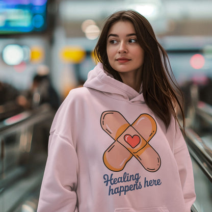 Woman wearing a pink hoodie with a bandage design and text in an indoor setting