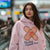 Woman wearing a pink hoodie with a bandage design and text in an indoor setting