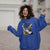 Woman wearing a blue hoodie with graphic design, standing outdoors.