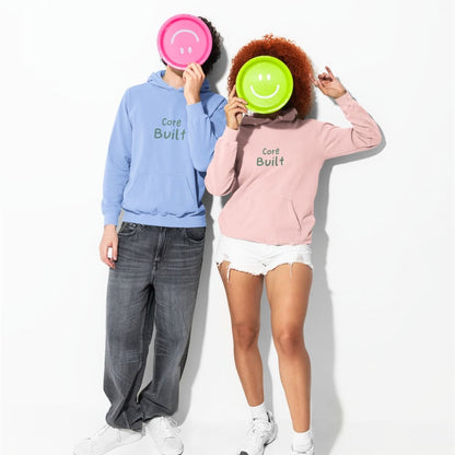 Two people wearing 'Core Built' hoodies with smiley face plates over their faces on a white background.
