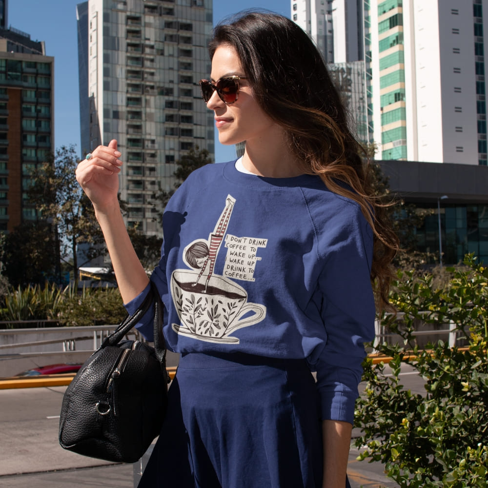 Woman wearing a blue sweatshirt with a coffee graphic in an urban setting