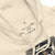 Close-up of a beige hoodie with a label and spider-Man graphic on a white background