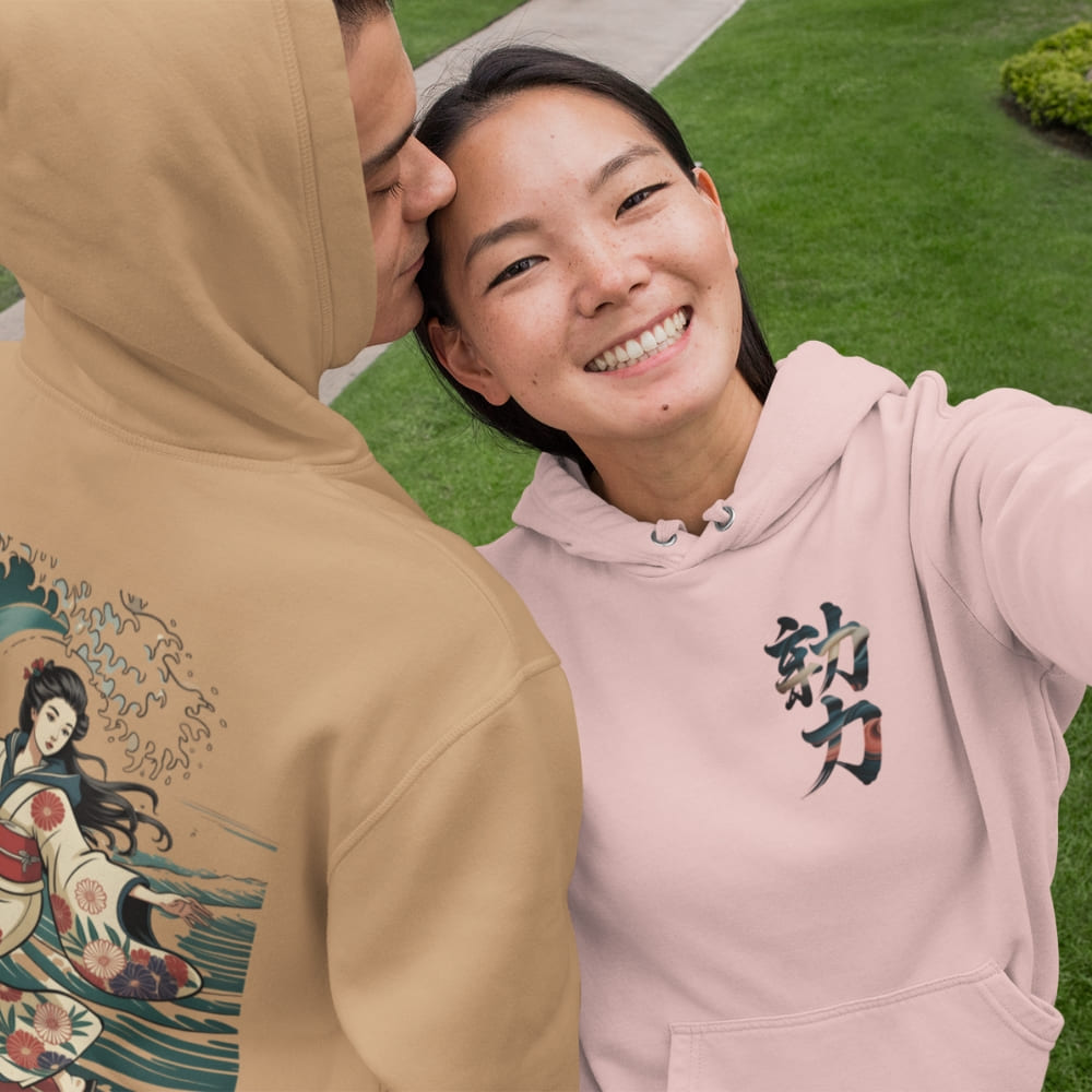 Two people wearing hoodies with unique designs, one beige with an illustration and one pink with text, outdoors.